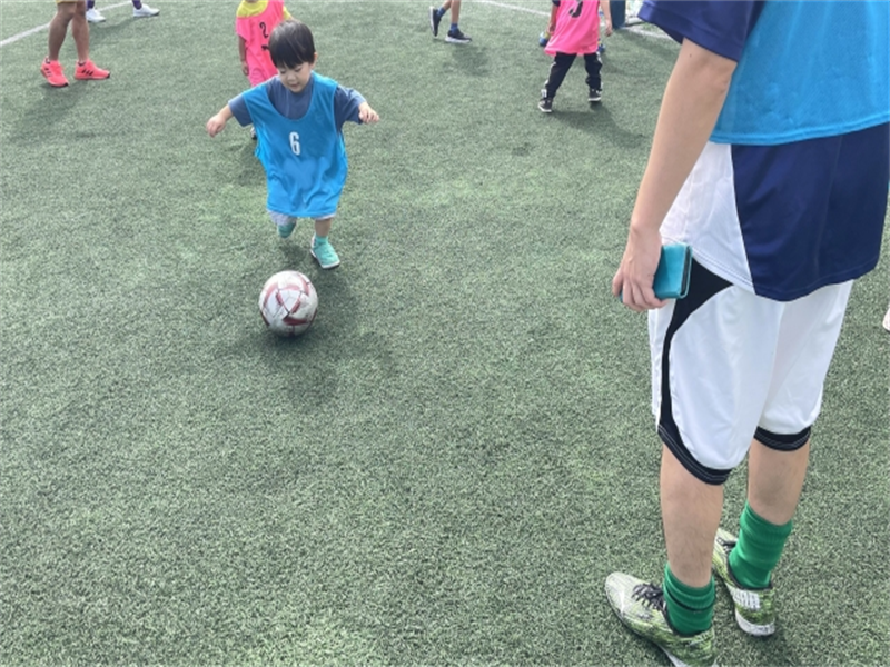 サッカースクールでボールを追いかける男の子