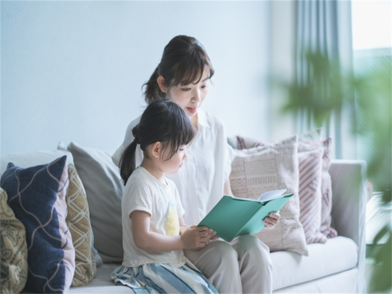 ソファで本を読む親子