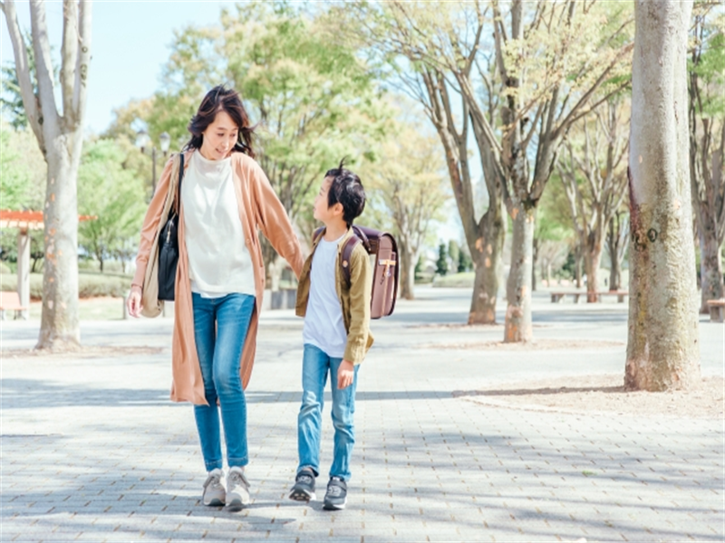 ランドセルを背負って母親と通学する小学生