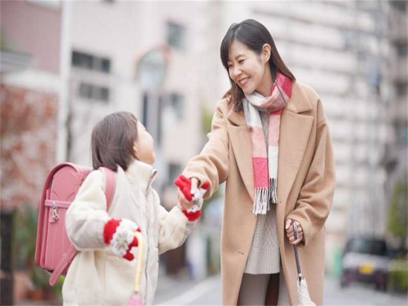 ランドセルを背負った子どもと手をつないで歩く母親